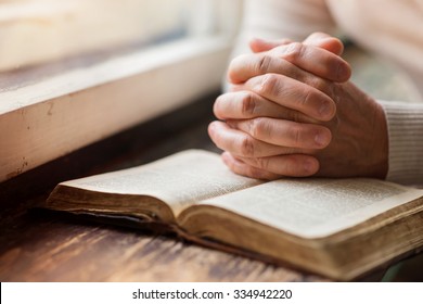Unrecognizable-woman-holding-a-bible-in-her-hands-and-praying-s334942220